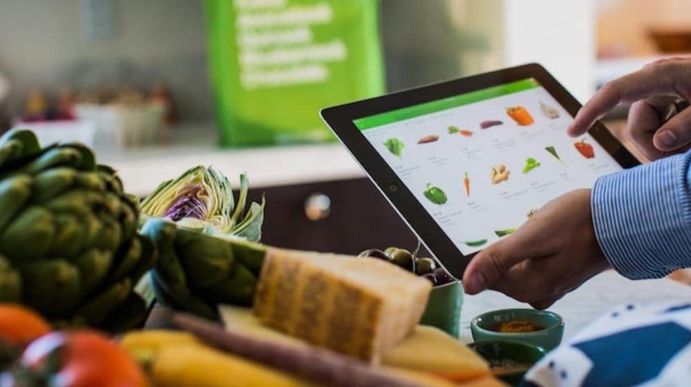 a hand holding a tablet which shows some kind of vegan food | Ask for Their Vegan Menu | Vegan Fast Food: Your Guide To Ordering Out