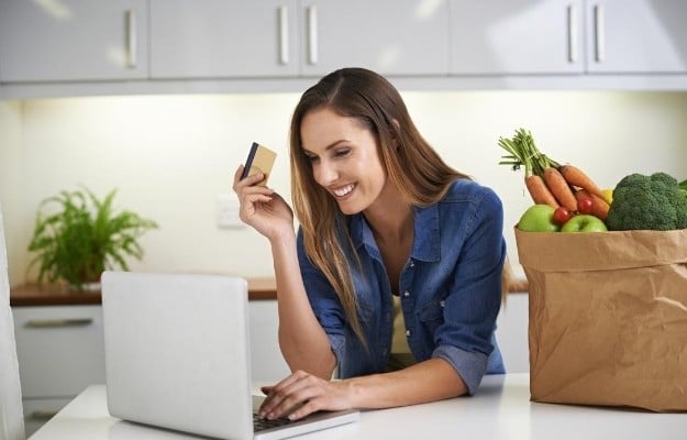 a woman smiling and holding credit card after ordering vegan food | Make An Online Review or Write on Their Comment Card | Vegan Fast Food: Your Guide for Ordering Out